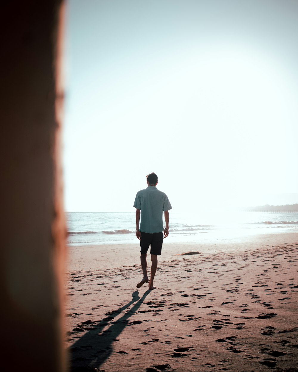 man in white shirt standing on beach during daytime