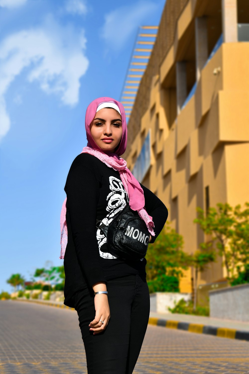 girl in black and white hoodie and pink knit cap standing near brown concrete building during