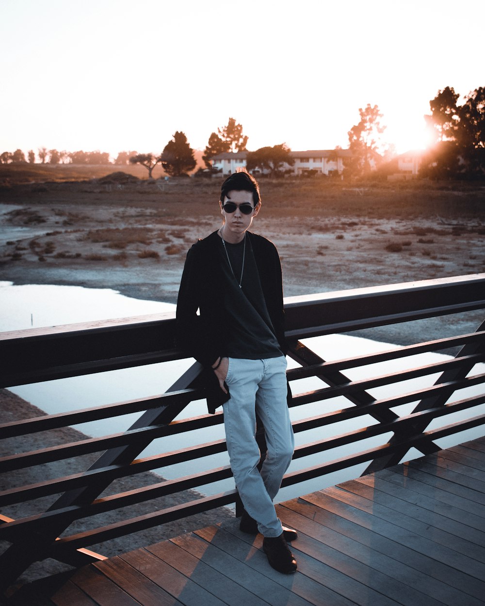 man in black jacket and white pants standing on wooden dock during daytime