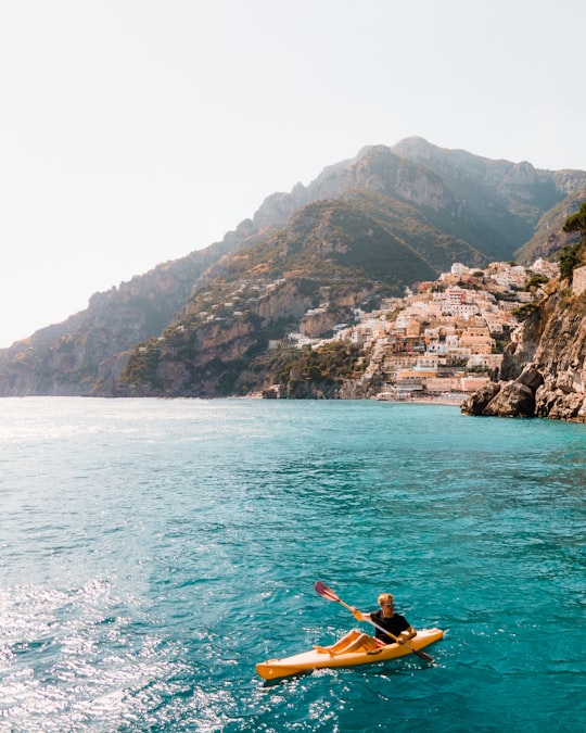man in red shirt riding on red kayak on sea during daytime in Amalfi Coast Italy