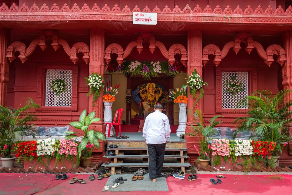 man in white dress shirt standing in front of red and white concrete building