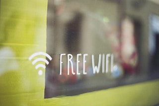 A sign with a Wi-Fi symbol and the text 'Free WiFi' displayed on a glass surface with a blurred background.