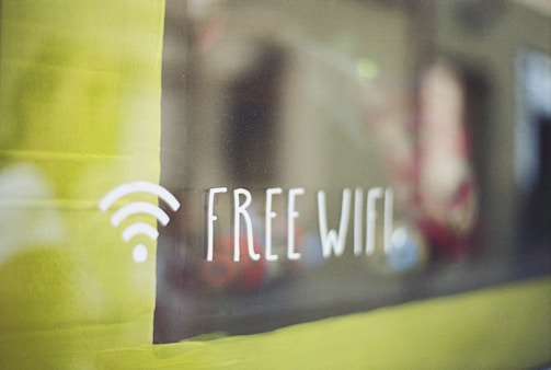A sign with a Wi-Fi symbol and the text 'Free WiFi' displayed on a glass surface with a blurred background.
