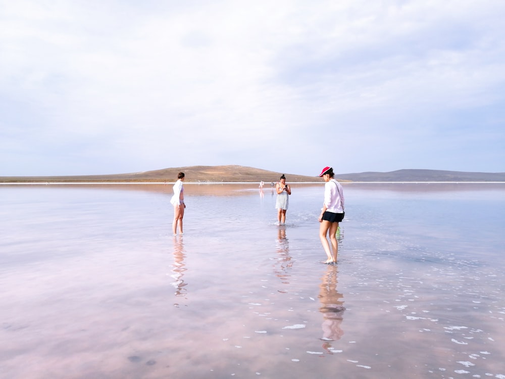 woman in white shirt and white shorts walking on beach during daytime