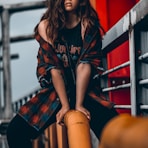 woman in black and red long sleeve shirt and black shorts sitting on yellow metal bar