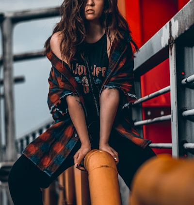 woman in black and red long sleeve shirt and black shorts sitting on yellow metal bar