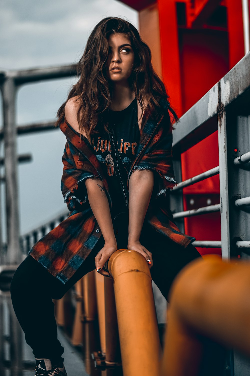 woman in black and red long sleeve shirt and black shorts sitting on yellow metal bar