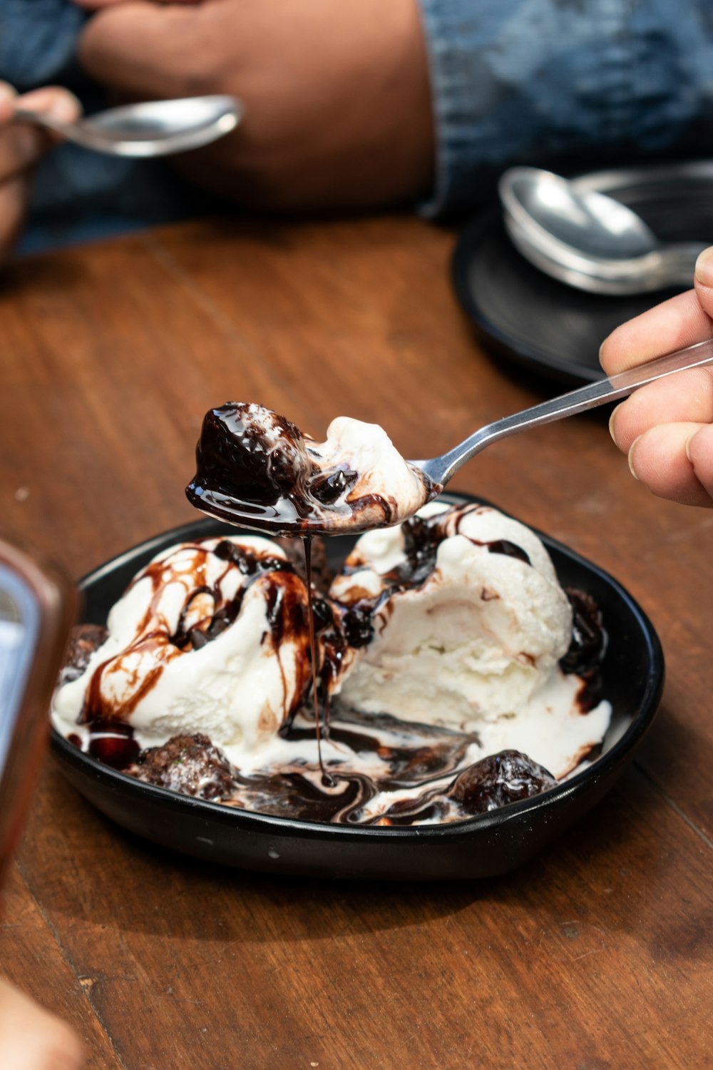 Helado con sirope de chocolate sobre mesa de madera marrón