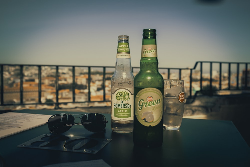 two green glass bottles on black table