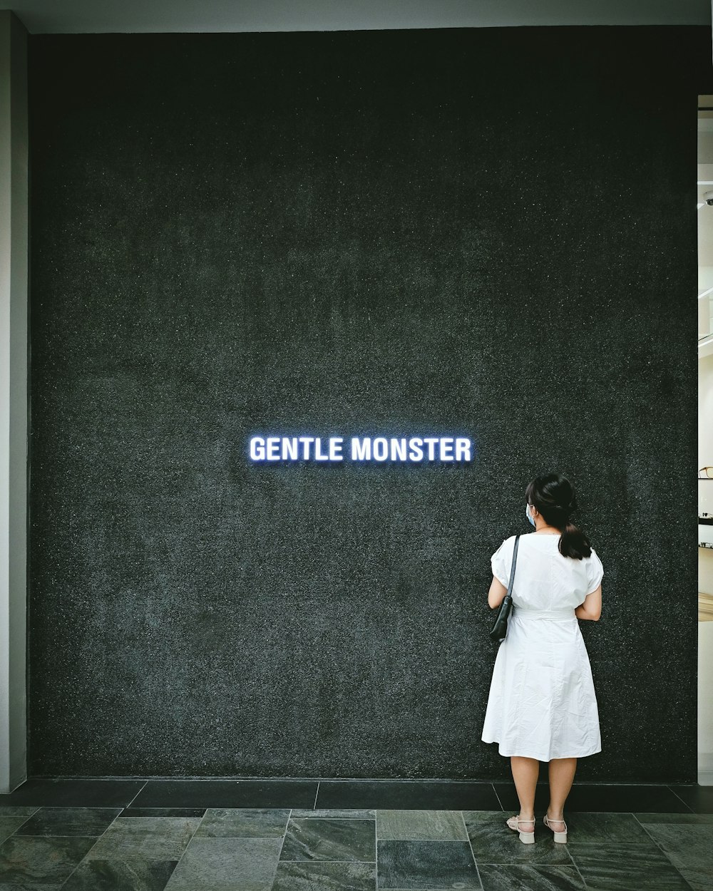 woman in white dress standing in front of black and white wall