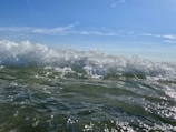 The image captures the movement of ocean waves, with water splashing and creating a dynamic interaction with light. The waves are vibrant and lively, reflecting sunlight and creating a shimmering effect.