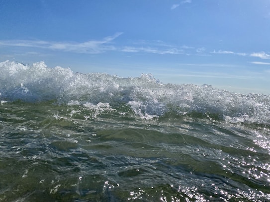 The image captures the movement of ocean waves, with water splashing and creating a dynamic interaction with light. The waves are vibrant and lively, reflecting sunlight and creating a shimmering effect.