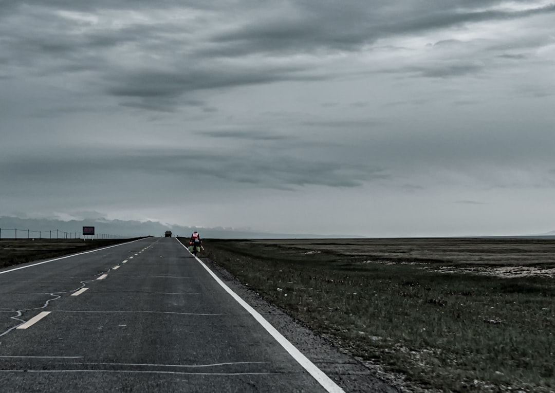 person in red jacket walking on gray asphalt road during daytime