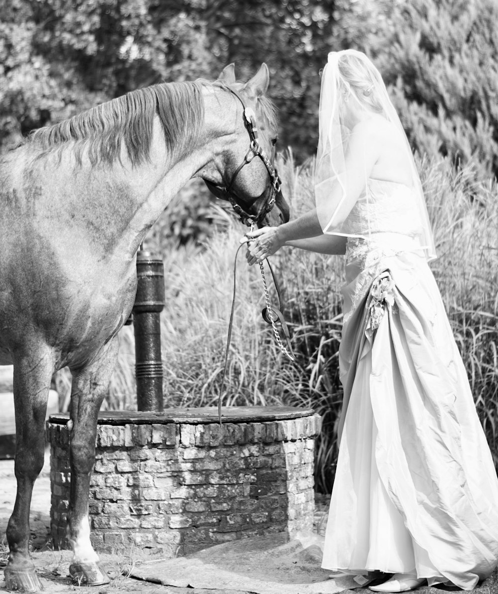 mujer con vestido blanco de pie junto al caballo