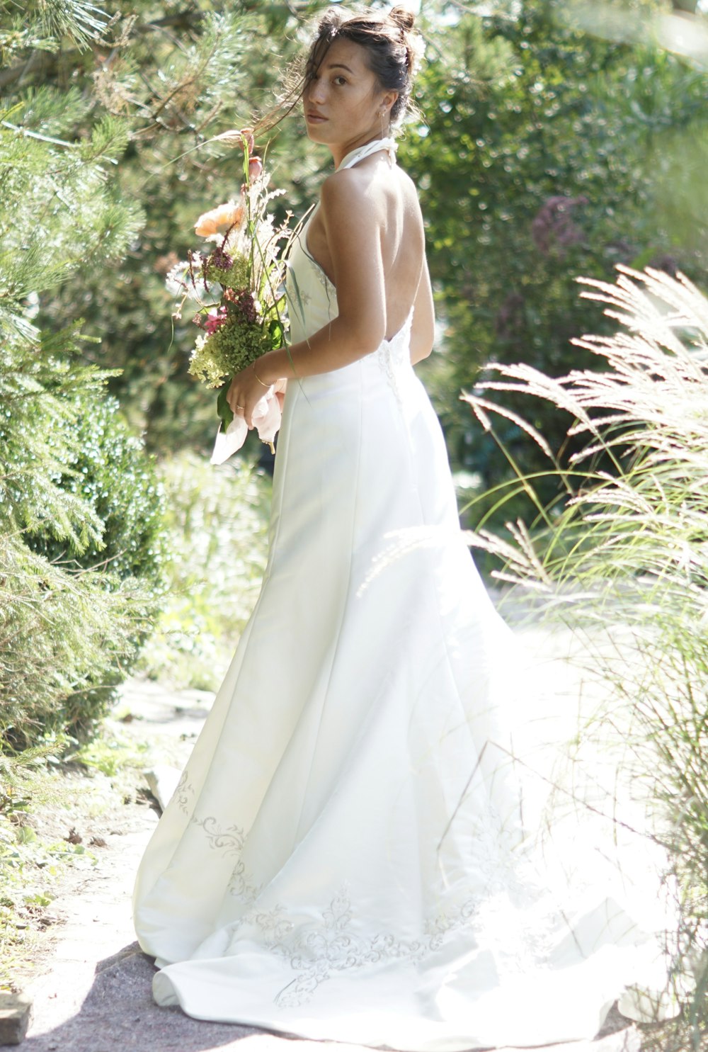 mujer en vestido de novia blanco sosteniendo ramo de flores