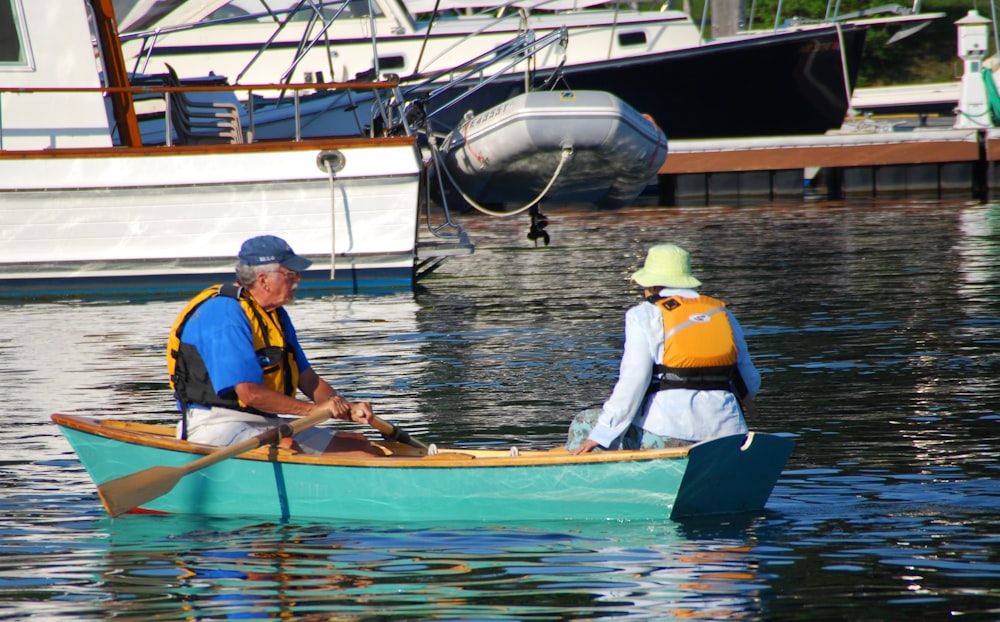 2 men in blue and yellow life vest riding on brown boat during daytime
