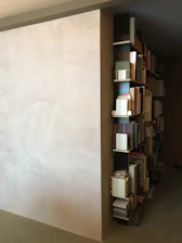 Finished modern bookshelf perfectly aligned on a white wall with warm lighting.