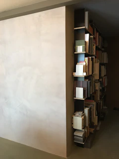 A modern bookshelf with a curated selection of books against a dark minimalist wall