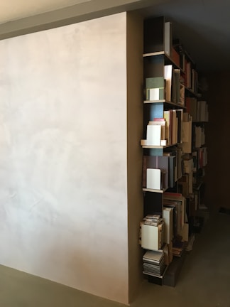 A minimalist bookshelf filled with books and decorative items against a clean white wall.