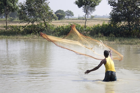 woman in black tank top and black shorts standing on water during daytime in Rajshahi Bangladesh