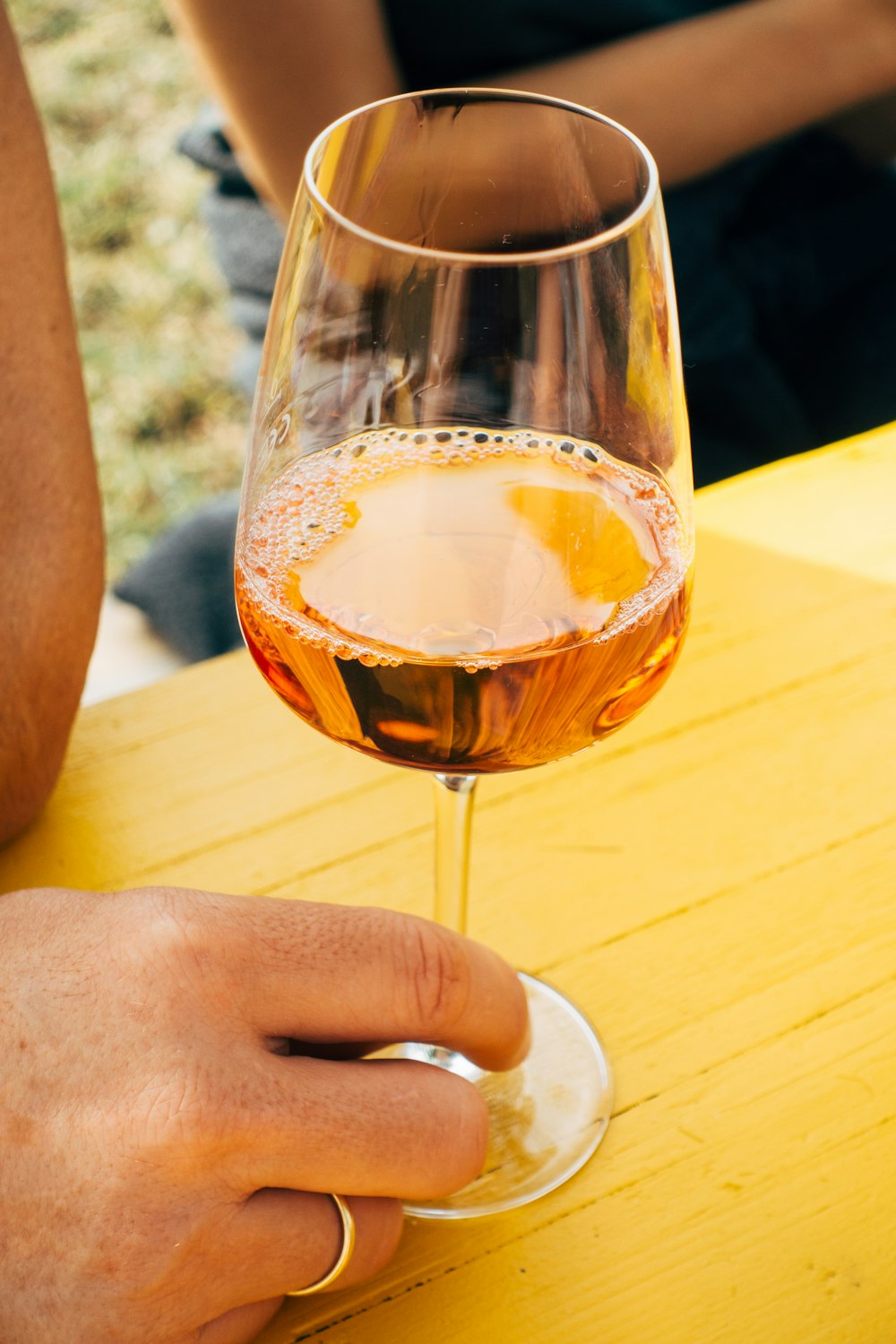 갈색 액체가 든 투명한 와인 잔을 들고 있는 사람