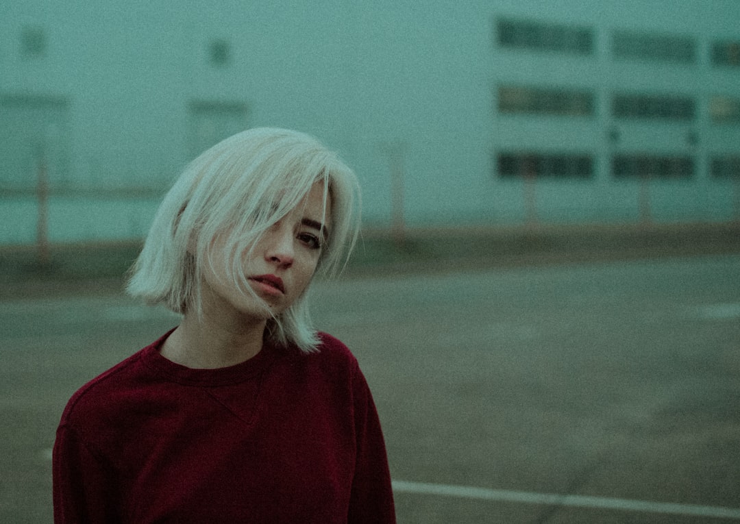 woman in red crew neck shirt standing on field during daytime