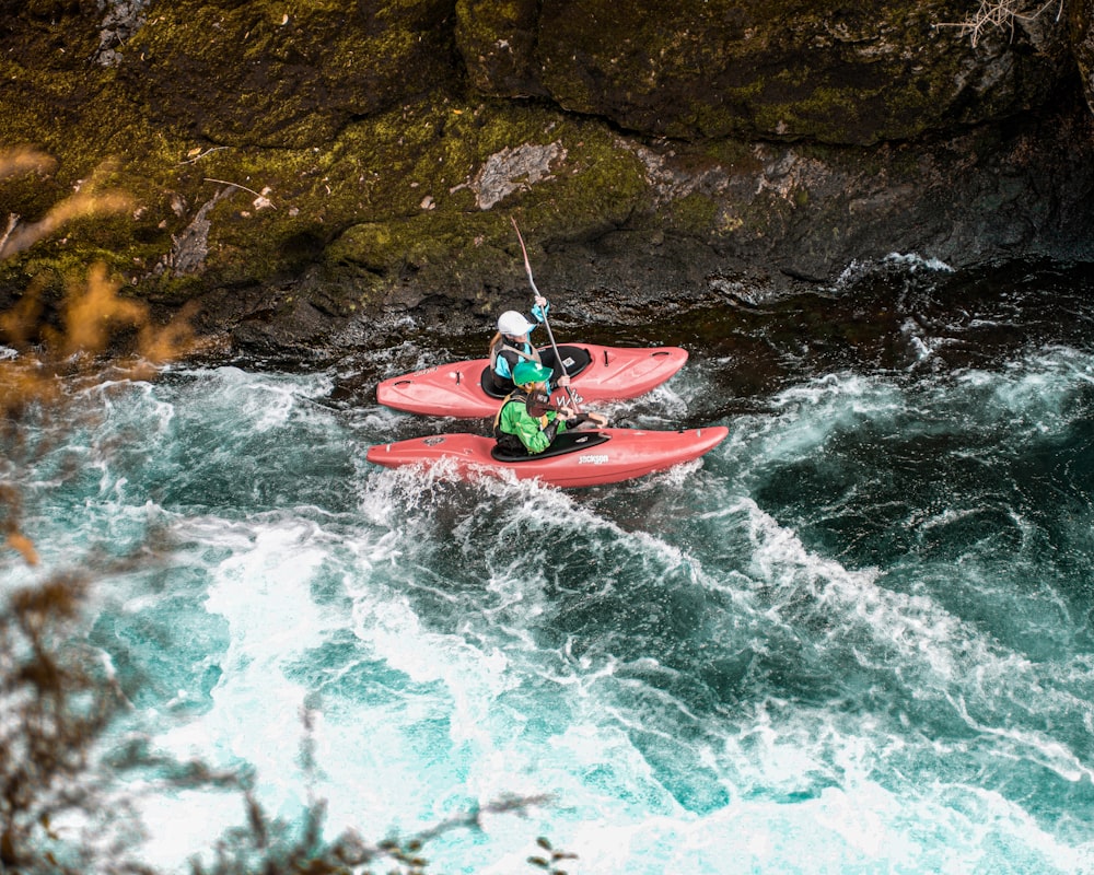 person riding red kayak on body of water during daytime