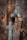 A metal water tap is attached to a rusty pipe, with a rope tied around the pipe. The background consists of a textured tree bark, providing a rustic and natural setting.