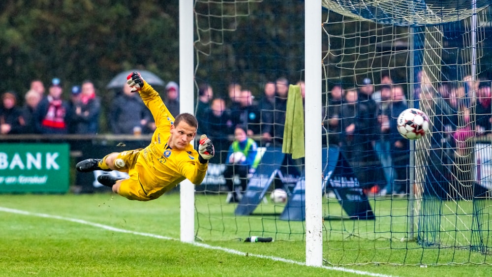 Mann in gelbem Langarmhemd und gelber Hose beim Fußballspielen