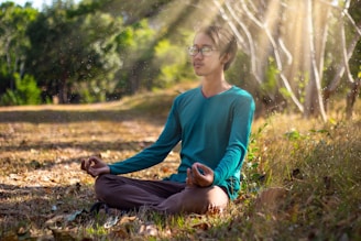 woman in blue long sleeve shirt and blue denim jeans sitting on ground during daytime