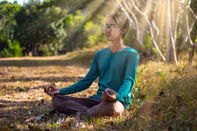 woman in blue long sleeve shirt and blue denim jeans sitting on ground during daytime