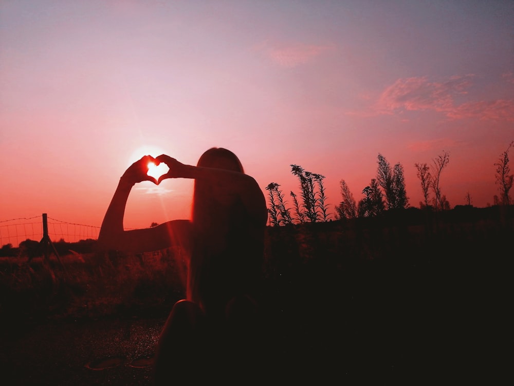 silhouette of man raising his hand during sunset