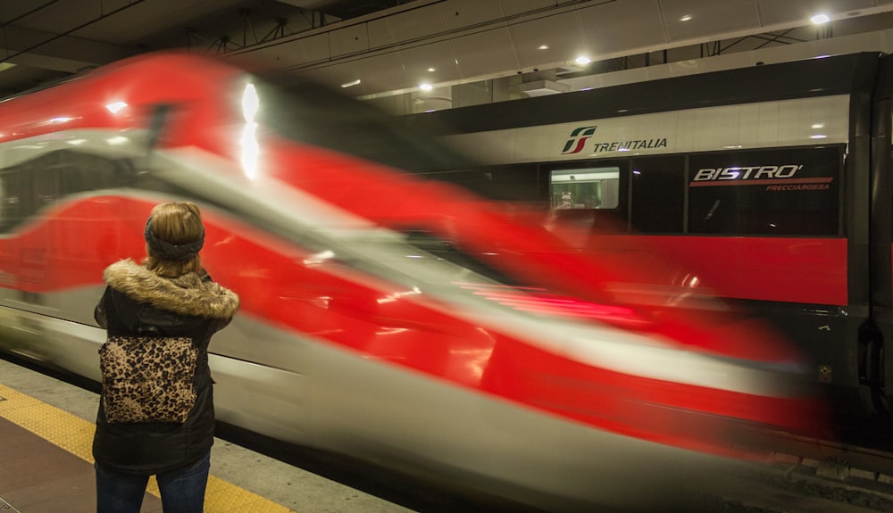 빨간색과 흰색 기차 근처에 서 있는 검은색 재킷을 입은 사람