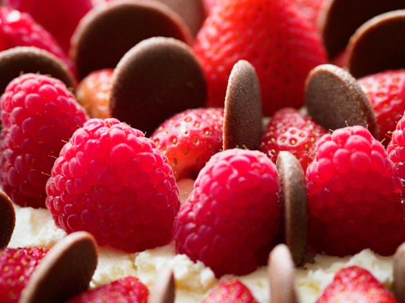 A vibrant display of chocolate-dipped strawberries and colorful fruit bouquets arranged elegantly on a white marble surface.