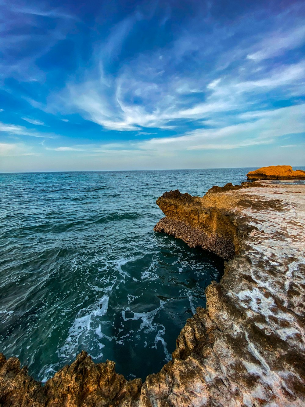 brown rock formation beside body of water during daytime