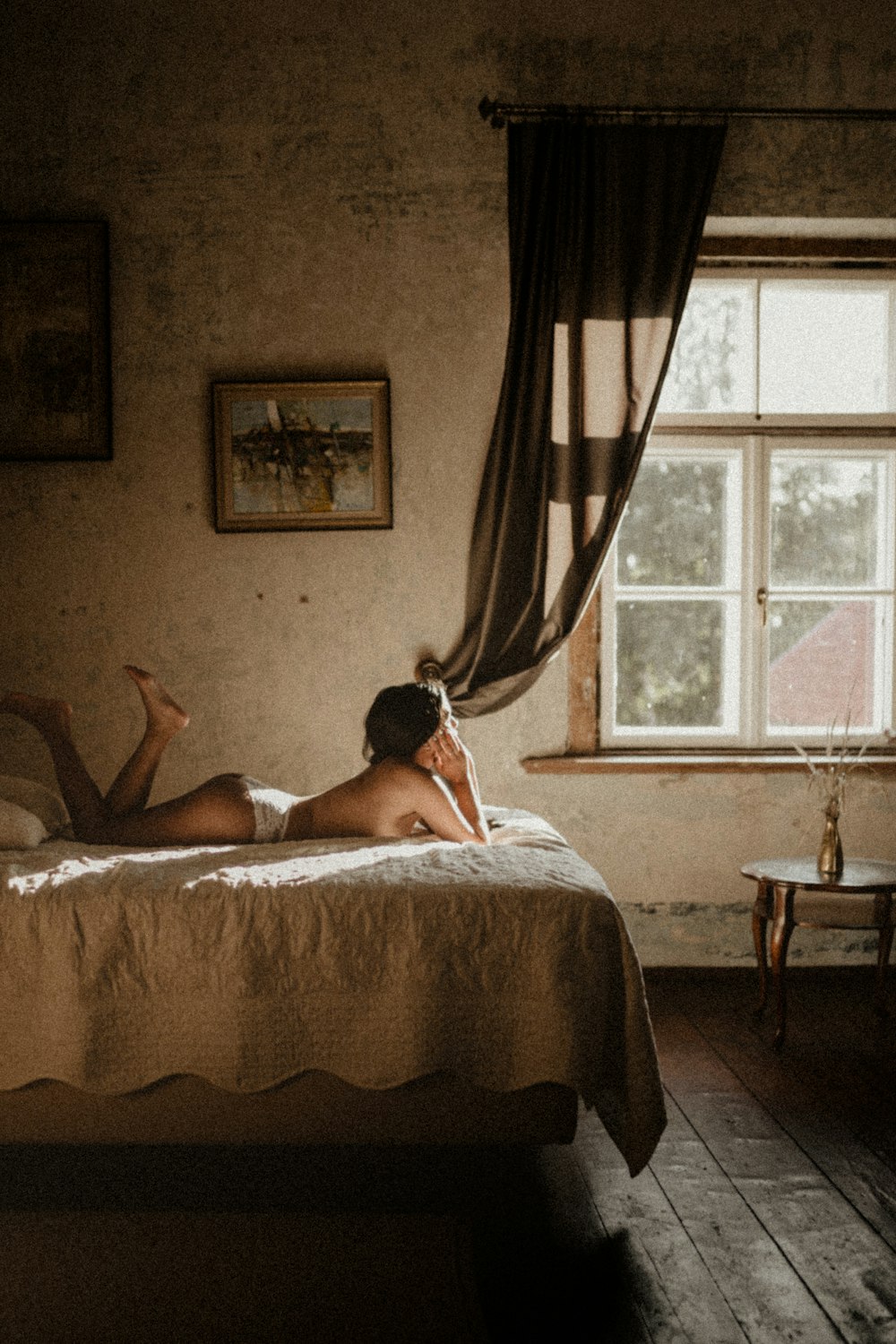 woman lying on bed near window
