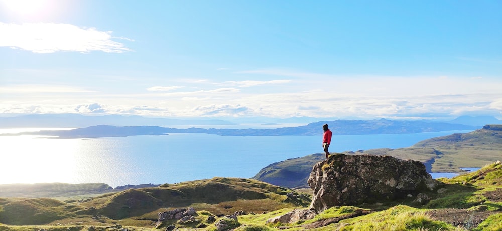 person in red jacket standing on rock formation during daytime