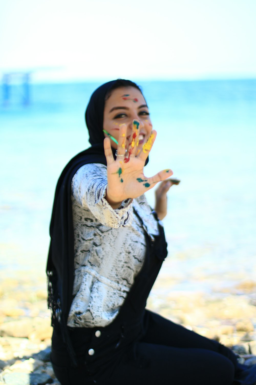 woman in black and white scarf covering her face with her hand