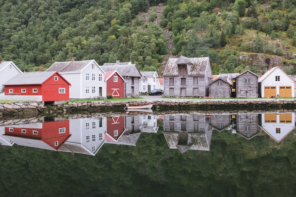 weißes und braunes Haus neben grünen Bäumen und See tagsüber