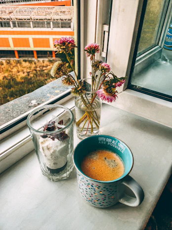 A cozy kitchen scene featuring a colorful sipstyled mug beside a small vase of fresh flowers.
