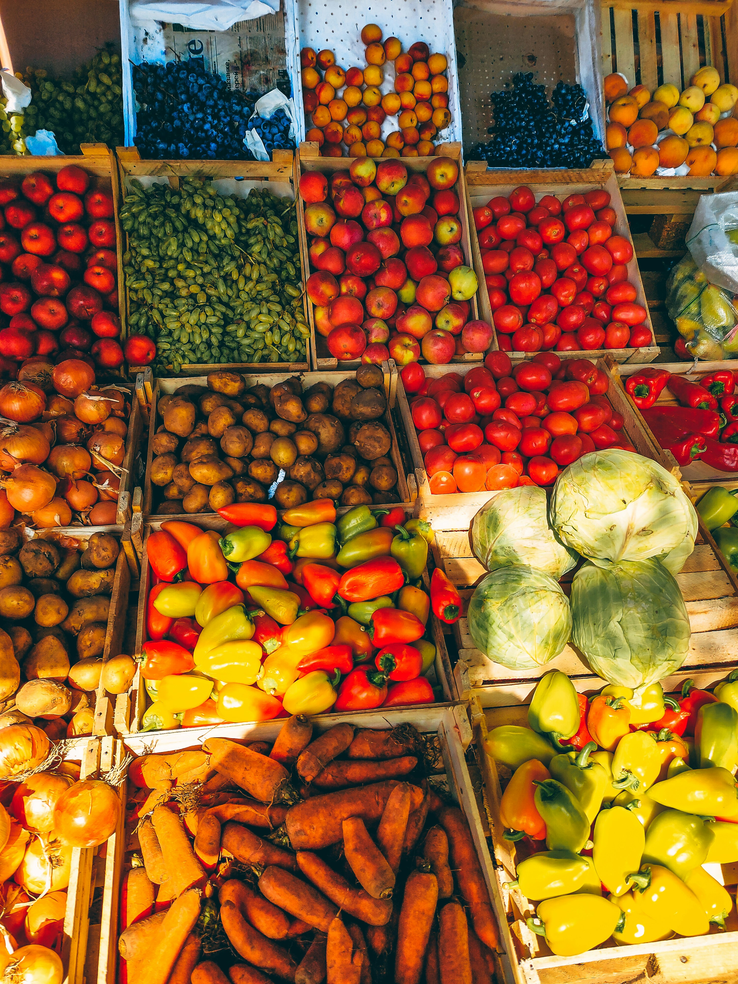 Fresh fruits in wooden crates at a sunlit market stall, warm morning light, abundant colorful produce