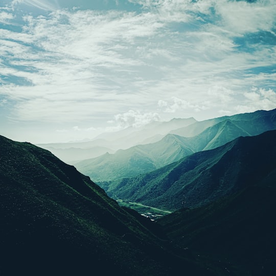 green mountains under white clouds during daytime in Xining China