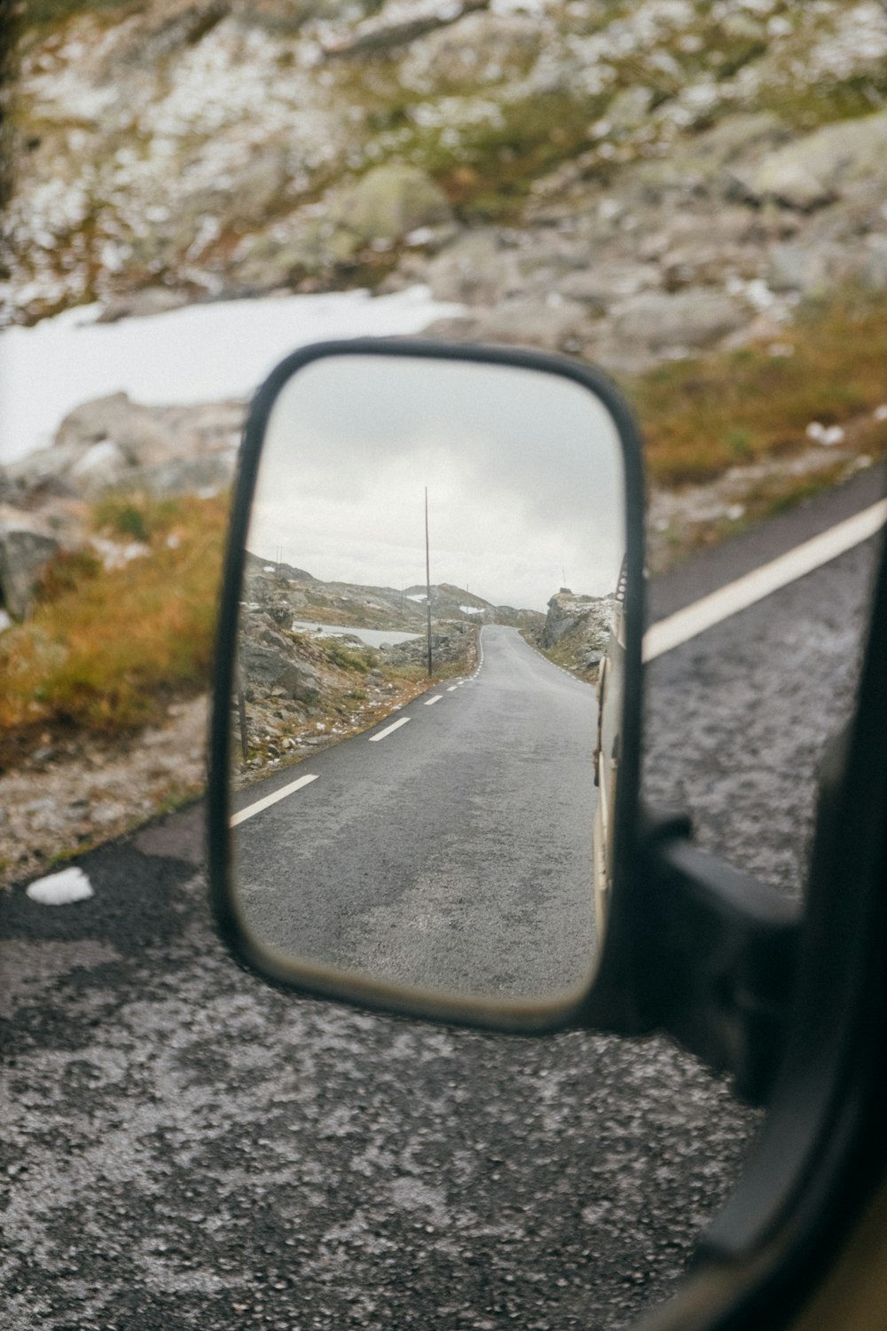 espelho lateral do carro com neve na estrada