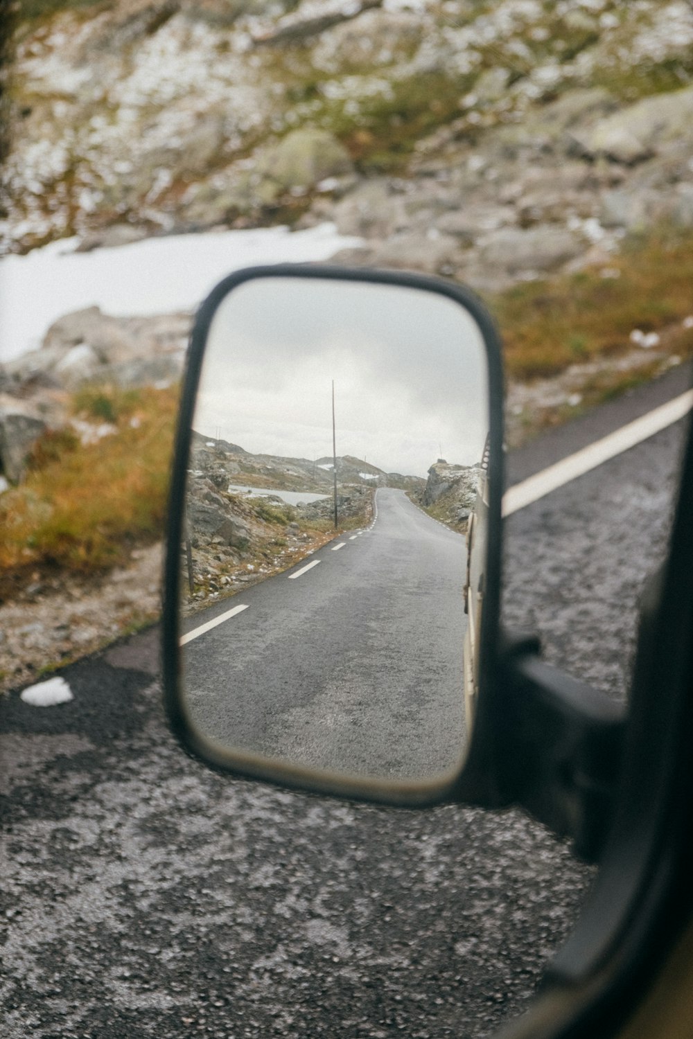 car side mirror with snow on the road