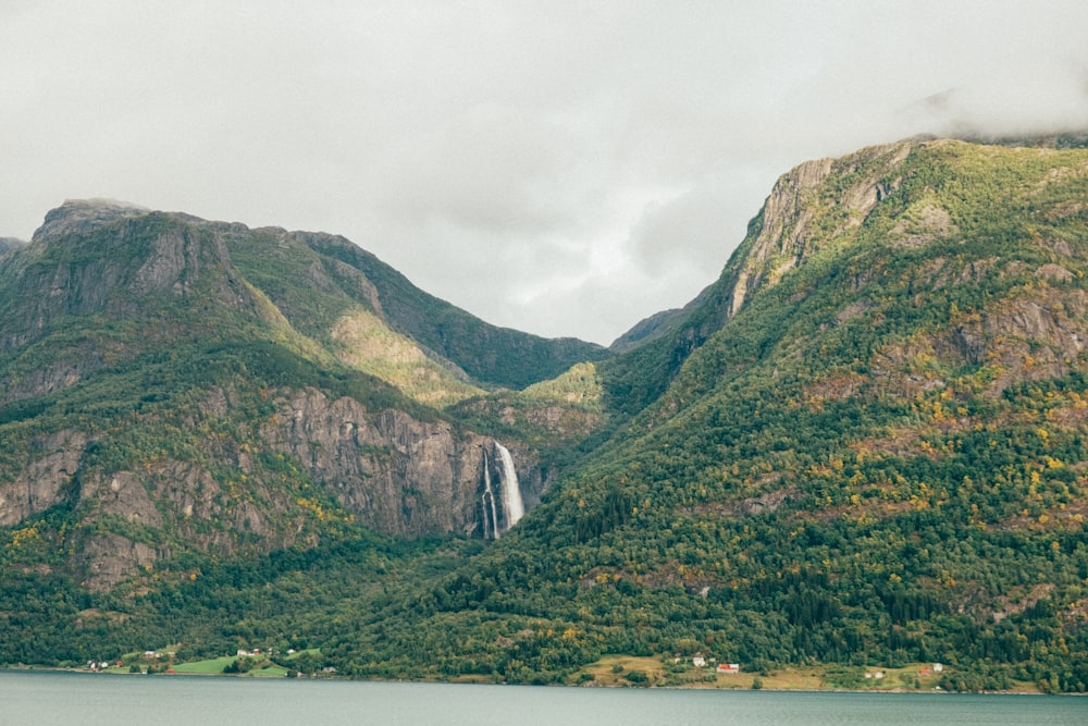 green and brown mountain beside body of water during daytime