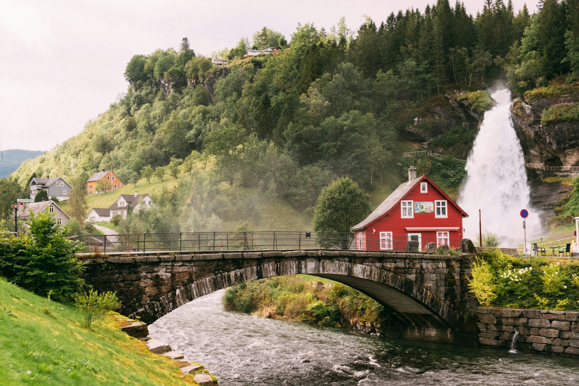 Norway waterfall and bridge overlooking a scenic small town surrounded by mountains