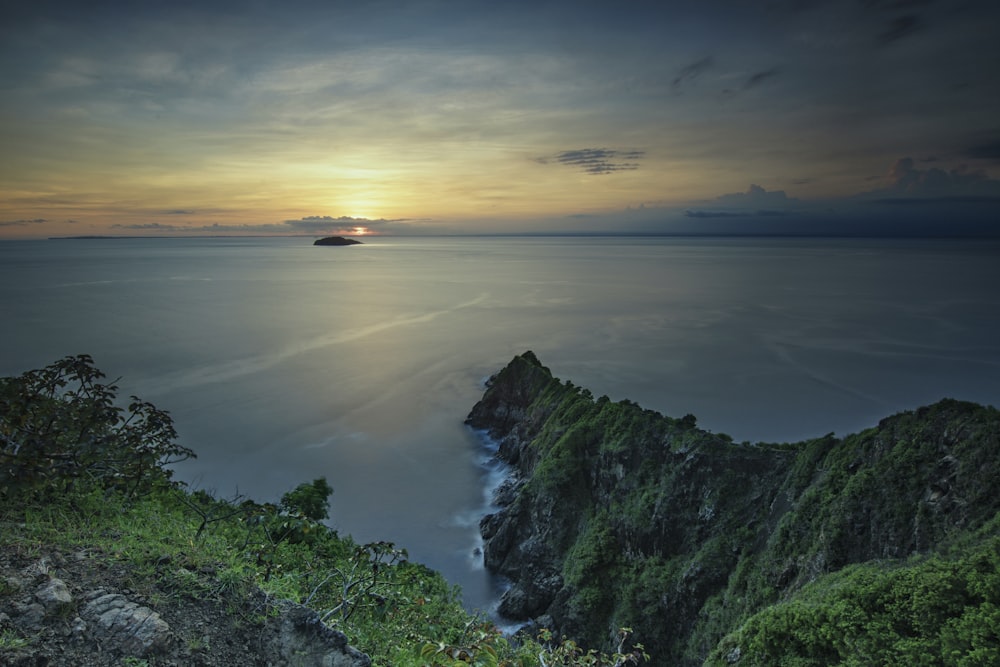 green and brown mountain beside body of water during sunset