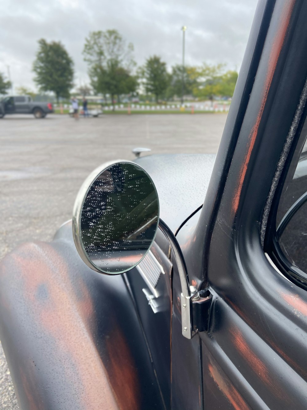 car side mirror showing car on road during daytime