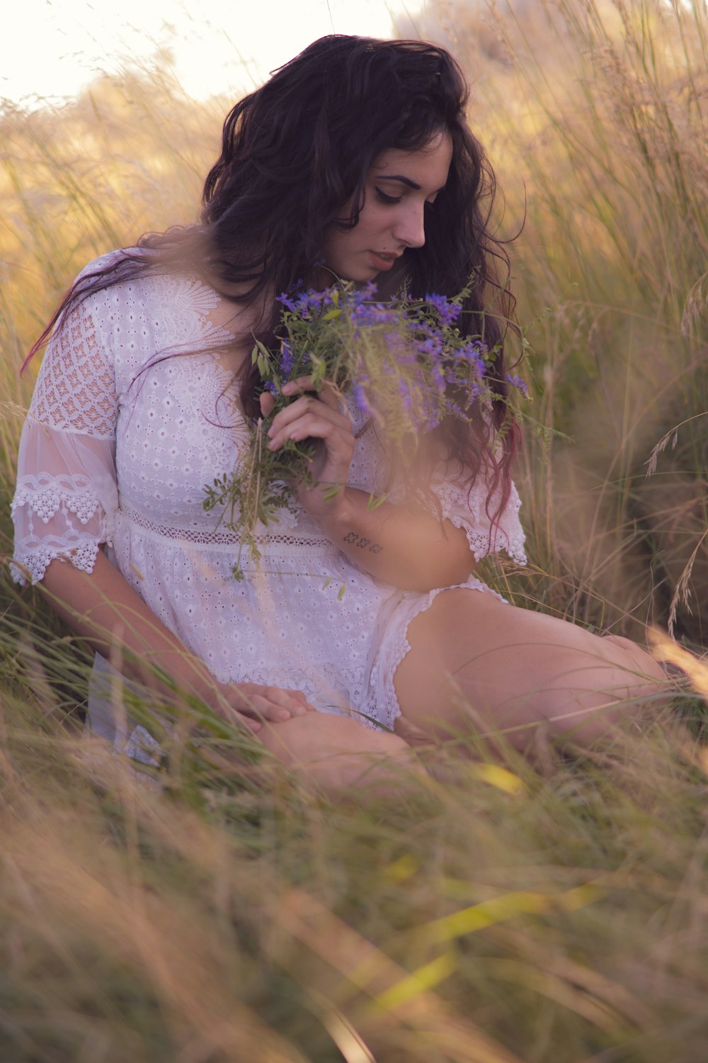 woman in white lace dress sitting on grass field