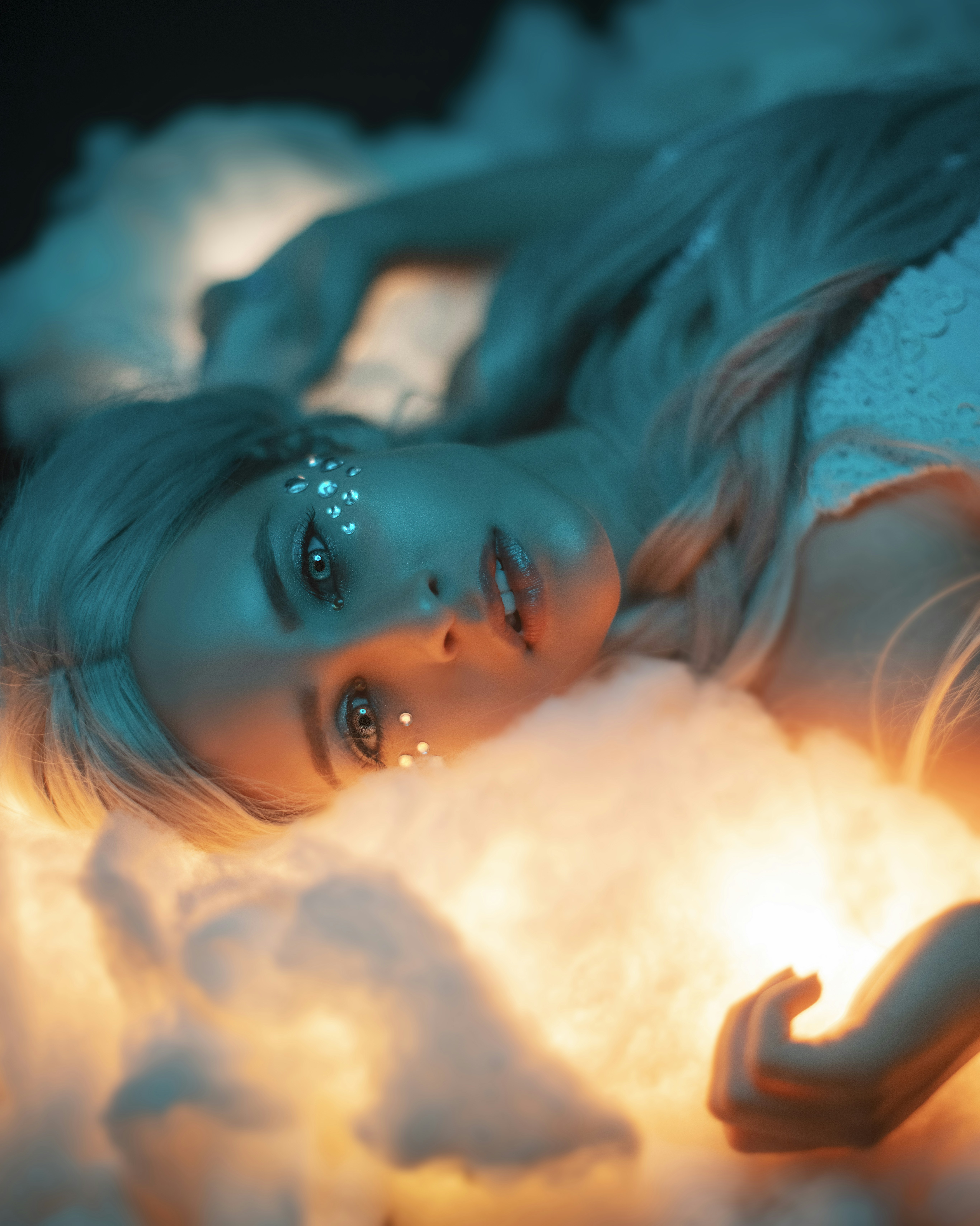 A woman with light blue eyes and blonde hair laying on her back, looking at the camera. 